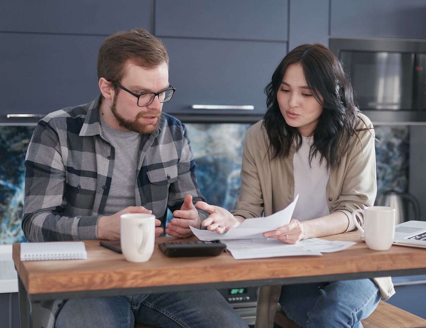 Two adults discussing paperwork at a kitchen table